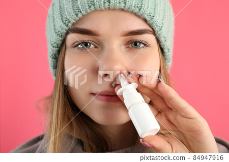 Young woman using nasal spray on pink background, runny nose concept 84947916