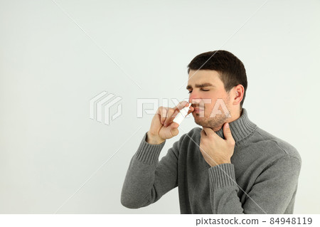 Young man with nasal spray on light background, runny nose concept 84948119