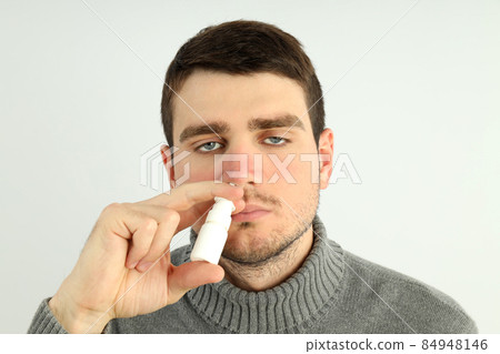 Young man with nasal spray on light background, runny nose concept 84948146