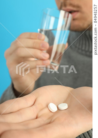 Young man is taking pills, seasonal cold concept 84948257