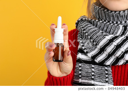 Young woman with nasal drops on yellow background, runny nose concept Young woman with nasal drops on yellow background, runny nose concept 84948403