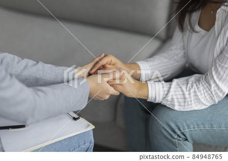 Professional compassion. Psychotherapist supporting depressed woman, holding her hands, sitting in clinic, cropped Professional compassion. Psychotherapist supporting depressed woman, holding her hands, sitting in clinic, cropped 84948765