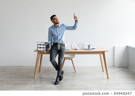 Happy Business Man Pointing Finger Up At Workplace Happy Business Man Pointing Finger Up At Workplace 84948847