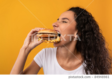 Funny Hungry Latin Lady Holding Burger Biting Sandwich At Studio 84948981