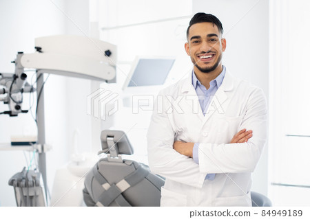 Dental Center. Portrait Of Smiling Middle Eastern Dentist Doctor Posing At Workplace Dental Center. Portrait Of Smiling Middle Eastern Dentist Doctor Posing At Workplace 84949189