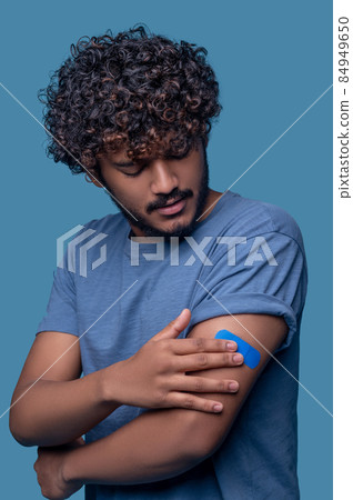 Male concentrated on examining his vaccination site 84949650