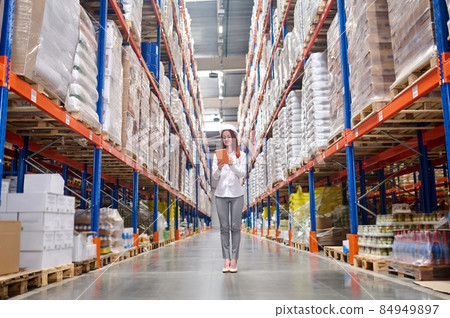 Elegant woman with tablet standing in warehouse aisle 84949897