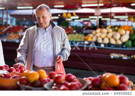 Middle aged man buying tomatoes Middle aged man buying tomatoes 84950082