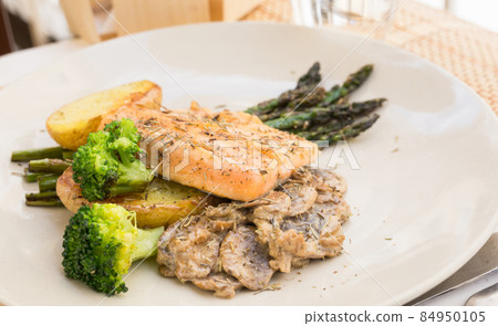 dish of fried river trout fillet with garnish of broccoli, asparagus sprouts and mushroom sauce 84950105