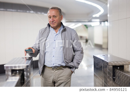 Middle aged man paying for entering subway with smartphone Middle aged man paying for entering subway with smartphone 84950121