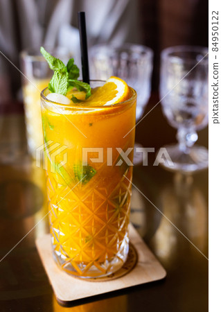 sea buckthorn cocktail with mint in a crystal glass on a table in a bar sea buckthorn cocktail with mint in a crystal glass on a table in a bar 84950122