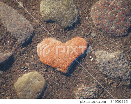Red stone heart on paved with big rocks road 84950315