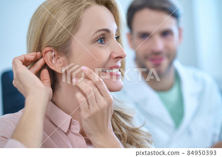 Profile of woman with her hands touching ear Profile of woman with her hands touching ear 84950393
