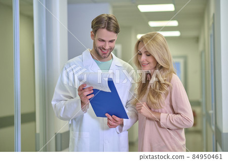 Man in white coat showing document to woman 84950461