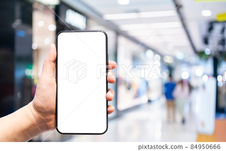 Close-up of female use Hand holding smartphone with empty blank white screen blurred images touch of Abstract blur of inside shopping complex background,shopping online concept. Close-up of female use Hand holding smartphone with empty blank white screen blurred images touch of Abstract blur of inside shopping complex background,shopping online concept. 84950666