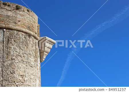 Ancient brick and stone light tower with triangular architectural element on a blue sky with a trail background 84951237