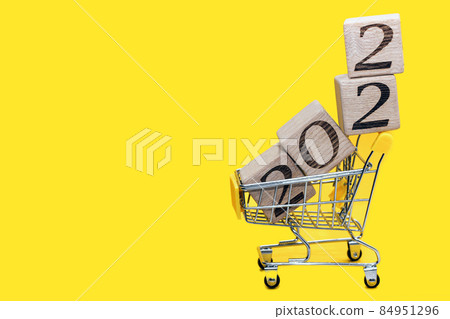 blocks 2022 in supermarket cart on yellow background. Christmas shopping blocks 2022 in supermarket cart on yellow background. Christmas shopping 84951296