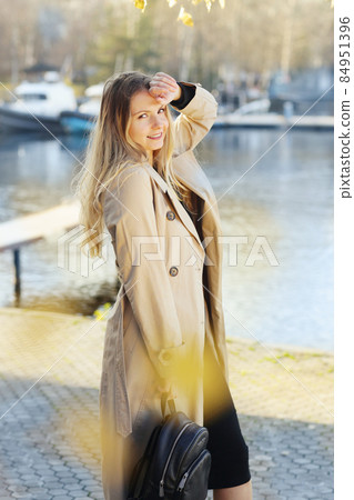 young blond slavic woman with long hair wearing trenchcoat street portrait with glasses on marina boat background young blond slavic woman with long hair wearing trenchcoat street portrait with glasses on marina boat background 84951396