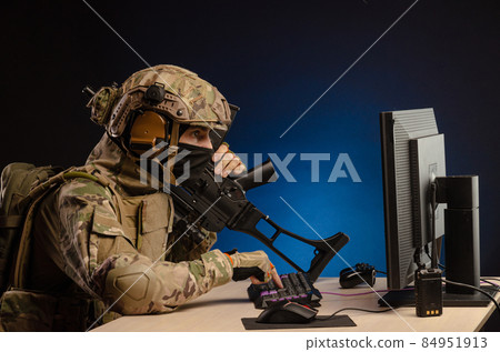 soldier sitting at a computer is conducting a cyber war 84951913