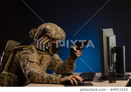 soldier sitting at a computer is conducting a cyber war 84951916