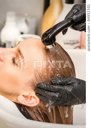 Young caucasian blonde woman having hair washed in the sink at a beauty salon. 84952101