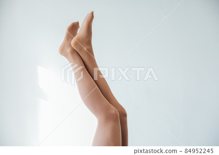 beautiful slender women's legs in tights stockings on a white background beautiful slender women's legs in tights stockings on a white background 84952245