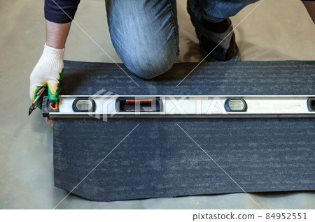 The master prepares a bituminous tape for installation, protection of a floor against moisture. 84952551
