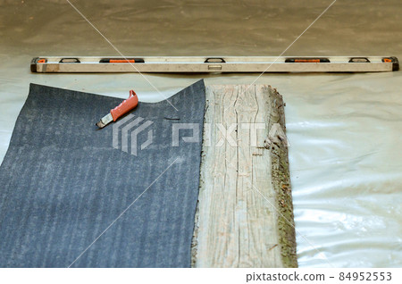 The master prepares a bituminous tape for installation, protection of a floor against moisture. 84952553