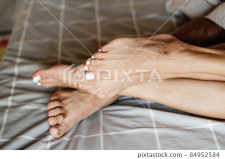 Two pairs of human legs in bed close up, man and woman lying in bed. Two pairs of human legs in bed close up, man and woman lying in bed. 84952584