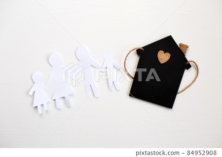 Happy paper cut family holding hands on wooden background near little toy house 84952908