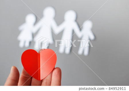 hand holding red heart on background of paper cut family 84952911