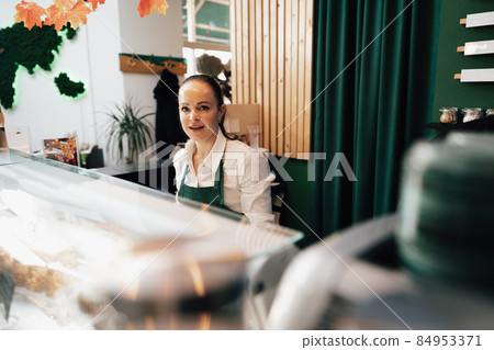 Young female barista standing inside the coffee counter Young female barista standing inside the coffee counter 84953371