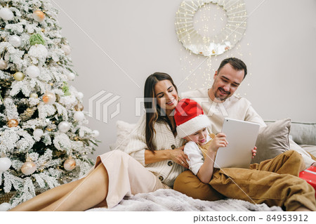 Happy family having fun on digital tablet in bed on Christmas Happy family having fun on digital tablet in bed on Christmas 84953912