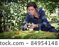 Girl taking pictures of nature in the forest on the big stone with moss 84954148