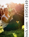A happy teenage girl sits on a lawn and plays with a dog to hug him 84954149