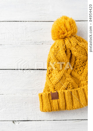 Yellow knitted hat on white wooden background. Top view 84954420
