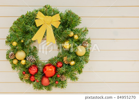Green Christmas fancy wreath hangs on a beige plank wall. Postcard with copy space Green Christmas fancy wreath hangs on a beige plank wall. Postcard with copy space 84955270