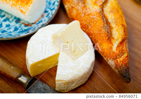 French cheese and fresh baguette on a wood cutter French cheese and fresh baguette on a wood cutter 84956071