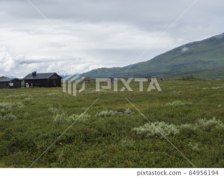 Lapland landscape at Virihaure lake with sami village Arasluokta houses, snow capped mountains and plain with shrubs. Sweden summer moody and foggy wild nature, Padjelantaleden hiking trail. Lapland landscape at Virihaure lake with sami village Arasluokta houses, snow capped mountains and plain with shrubs. Sweden summer moody and foggy wild nature, Padjelantaleden hiking trail. 84956194