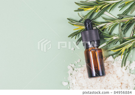 Rosemary essential oil bottle next to fresh branches of rosemary 84956884