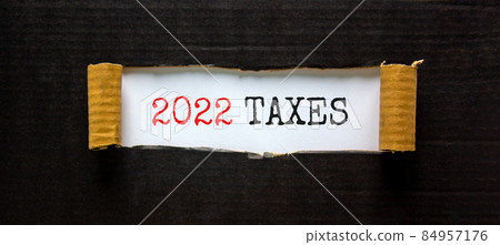 2022 taxes new year symbol. Words '2022 taxes' appearing behind torn black paper. Beautiful black background. Business, 2022 taxes new year concept, copy space. 2022 taxes new year symbol. Words '2022 taxes' appearing behind torn black paper. Beautiful black background. Business, 2022 taxes new year concept, copy space. 84957176