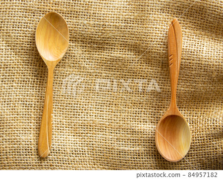 Two beautiful wooden spoons isolated on canvas background. Two beautiful wooden spoons isolated on canvas background. 84957182