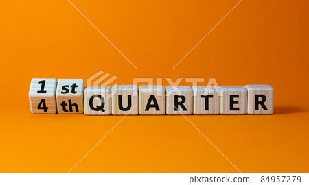 From 4th to 1st quater symbol. Turned wooden cubes and changed words '4th quater' to '1st quater'. Beautiful orange table, orange background. Business, happy 1st quater concept, copy space. 84957279