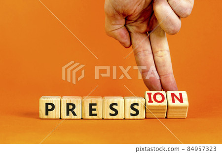 Pression to free press symbol. Businessman turns wooden cubes, changes the word pression to press. Beautiful orange table, orange background. Business and pression to free press concept. Copy space. 84957323