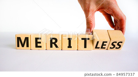 Merit or meritless symbol. Businessman turns wooden cubes and changes the word meritless to merit. Beautiful white table, white background. Business and merit or meritless concept. Copy space. 84957337