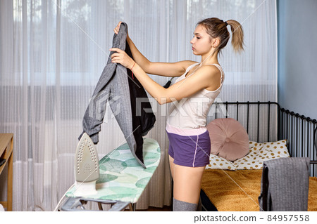 An ironing board and iron are used by young woman to smooth out her business suit before an interview. An ironing board and iron are used by young woman to smooth out her business suit before an interview. 84957558