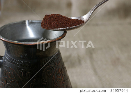 Turkish coffee pot and spoon with ground coffee. Turkish coffee pot and spoon with ground coffee. 84957944