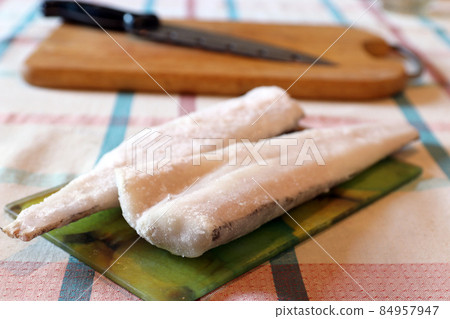 Several slices of frozen fish on glass cutting board Several slices of frozen fish on glass cutting board 84957947