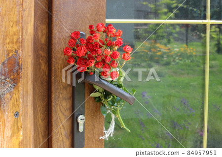 Bouquet of red roses on the front door of the house. Bouquet of red roses on the front door of the house. 84957951