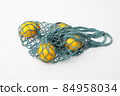 Lemons in a string bag on a light background. 84958034
